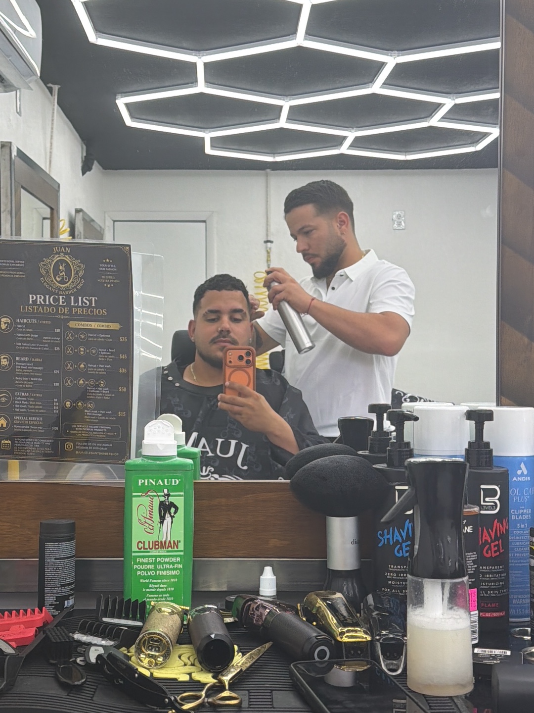 Juan working with a client, reflected in the barbershop mirror